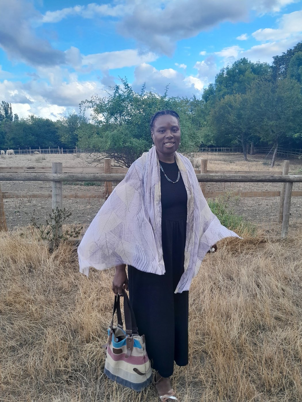 Eruvwu Obuaya at Mudchute Park and Farm, sheep grazing in the paddock behind her